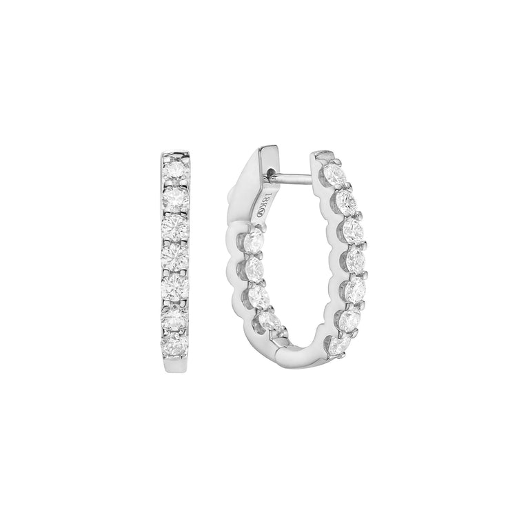 Close up view of the white gold prong-set diamond hoop earrings. Showcasing inside-out diamond detailing and a scalloped setting.