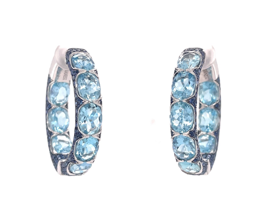 Close up view of the Aquamarine Hoop Earrings. Featuring oval aquamarine gemstones and small round blue sapphire gemstones set in 18k white gold.