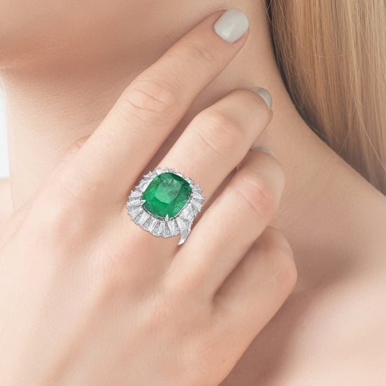 Close up view of the Green emerald ring with diamonds positioned on a finger.